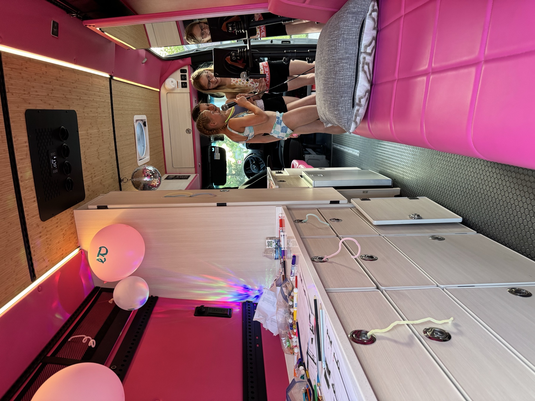 Friends enjoying a karaoke birthday party inside the pink Dream Van